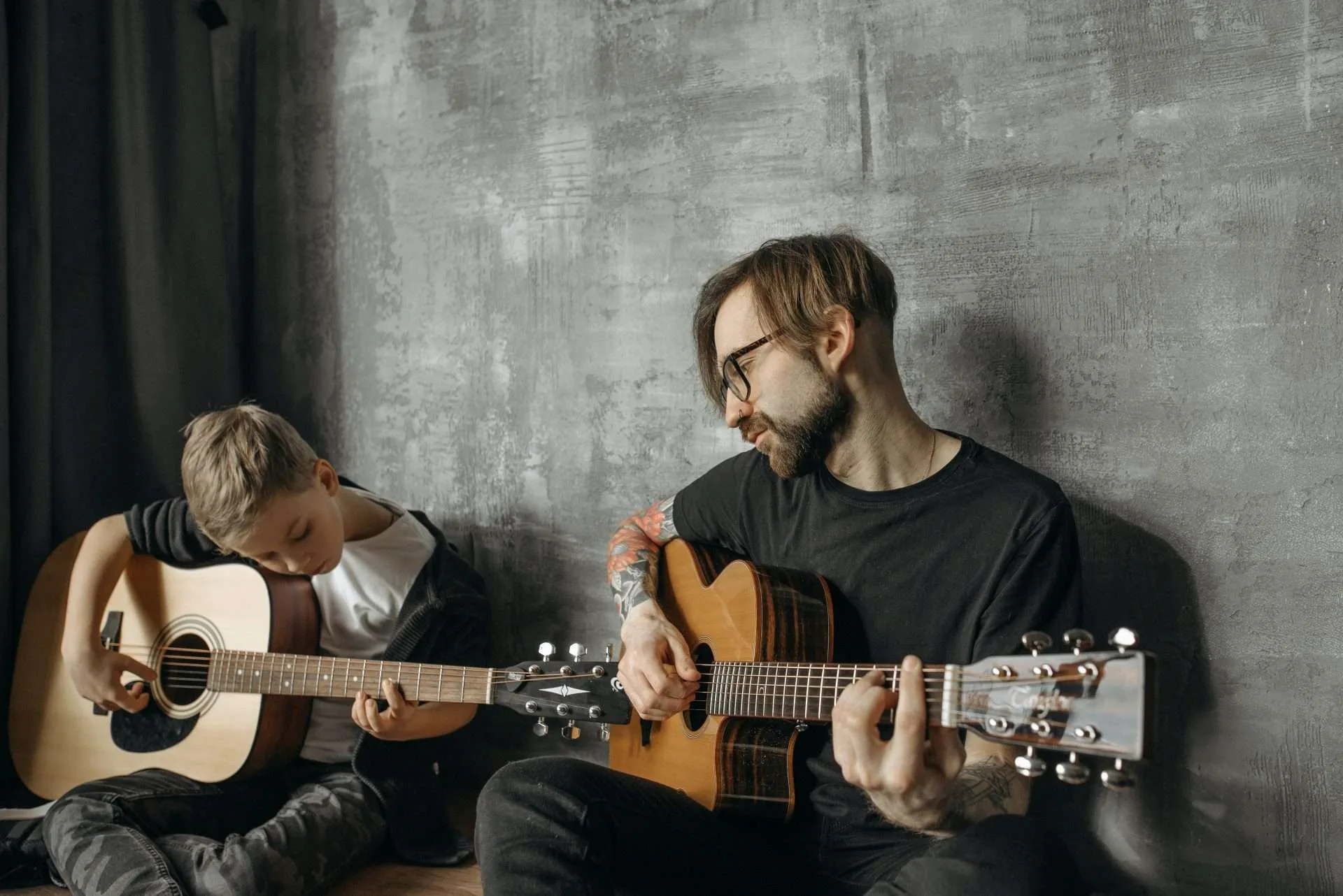 man teaching a young boy how to play the acoustic guitar