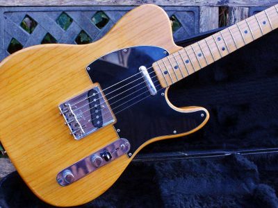 A telecaster body, 16 inches wide, 12.75 inches long, and 1.75 inches thick, with a distinct waist and rounded edges, sits on a workbench